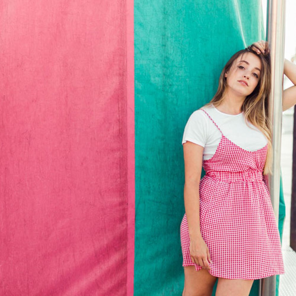 Smiling woman leaning on a pink and green wall